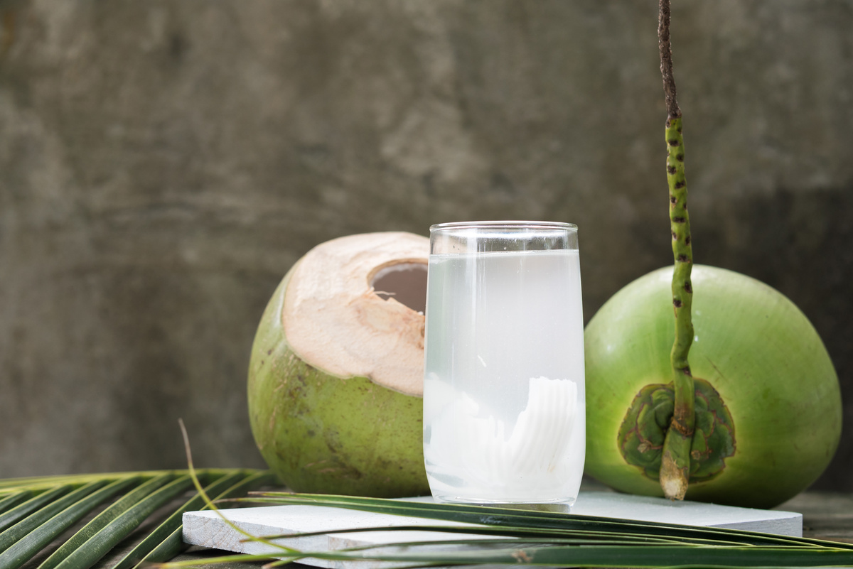 Cocos em mesa, com copo cheio de sua água.