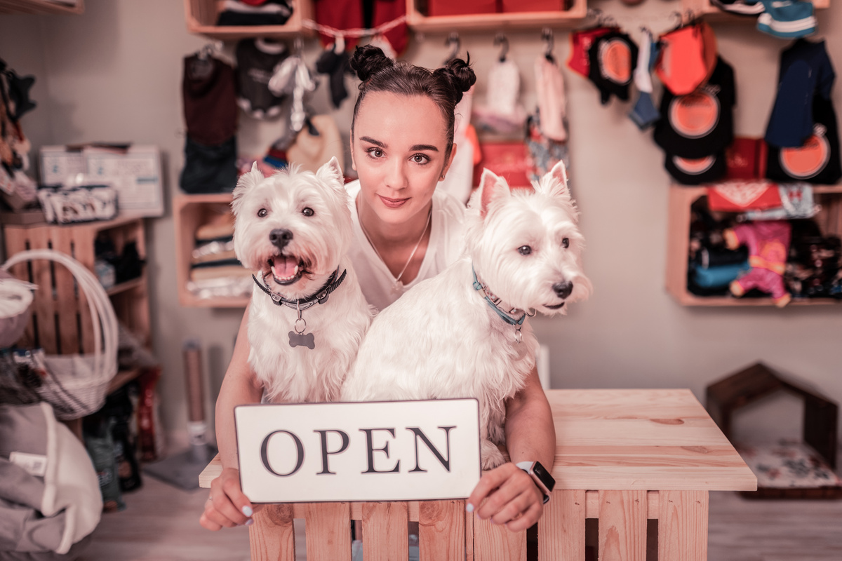 Mulher abraçada com dois cachorros em pet shop