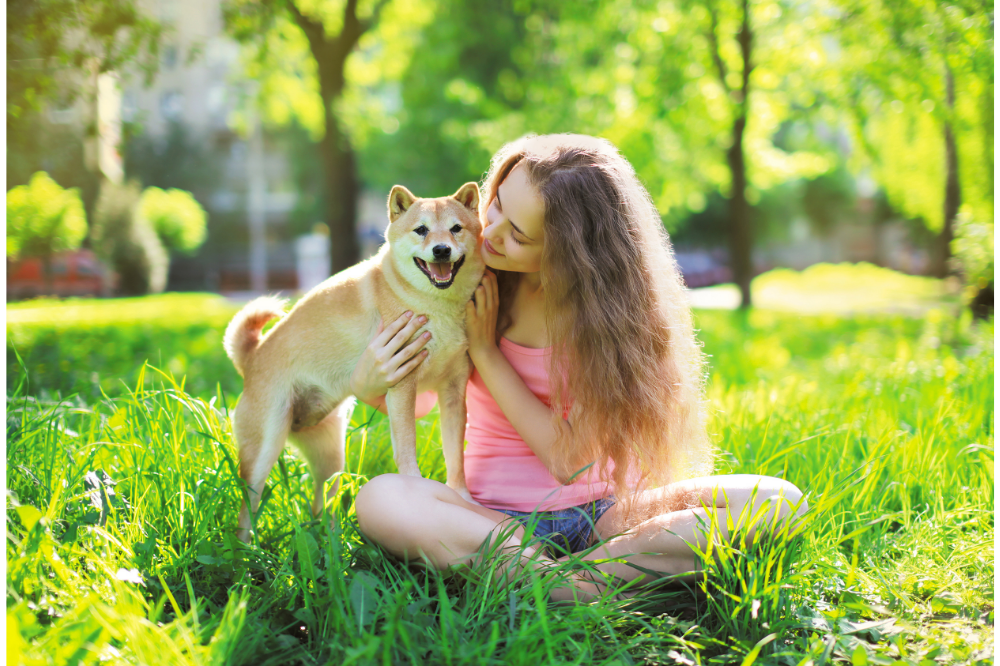 Uma mulher sentada na grama com o seu cachorro